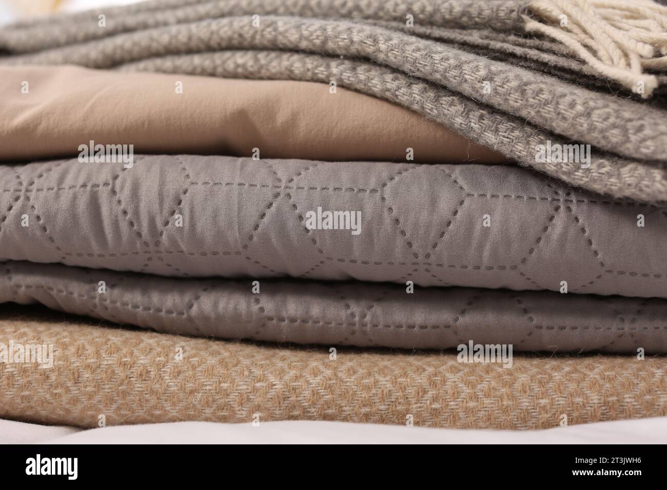 Stack of different folded blankets, closeup. Home textile Stock Photo