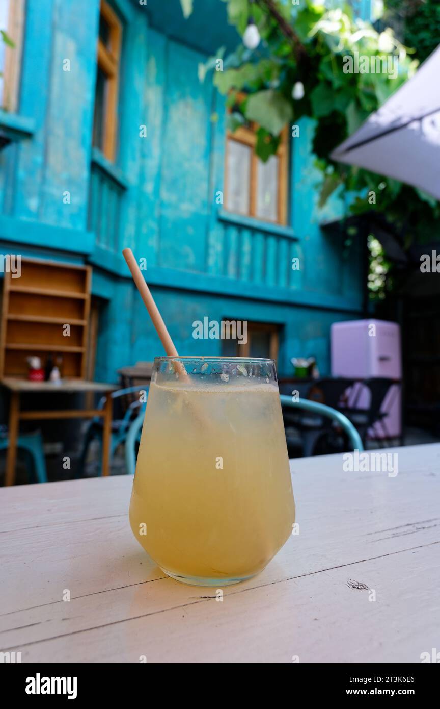 Freshly squeezed orange juice with a biodegradable brown straw, to be enjoyed in an open courtyard adorned with blue walls in the backdrop. Stock Photo