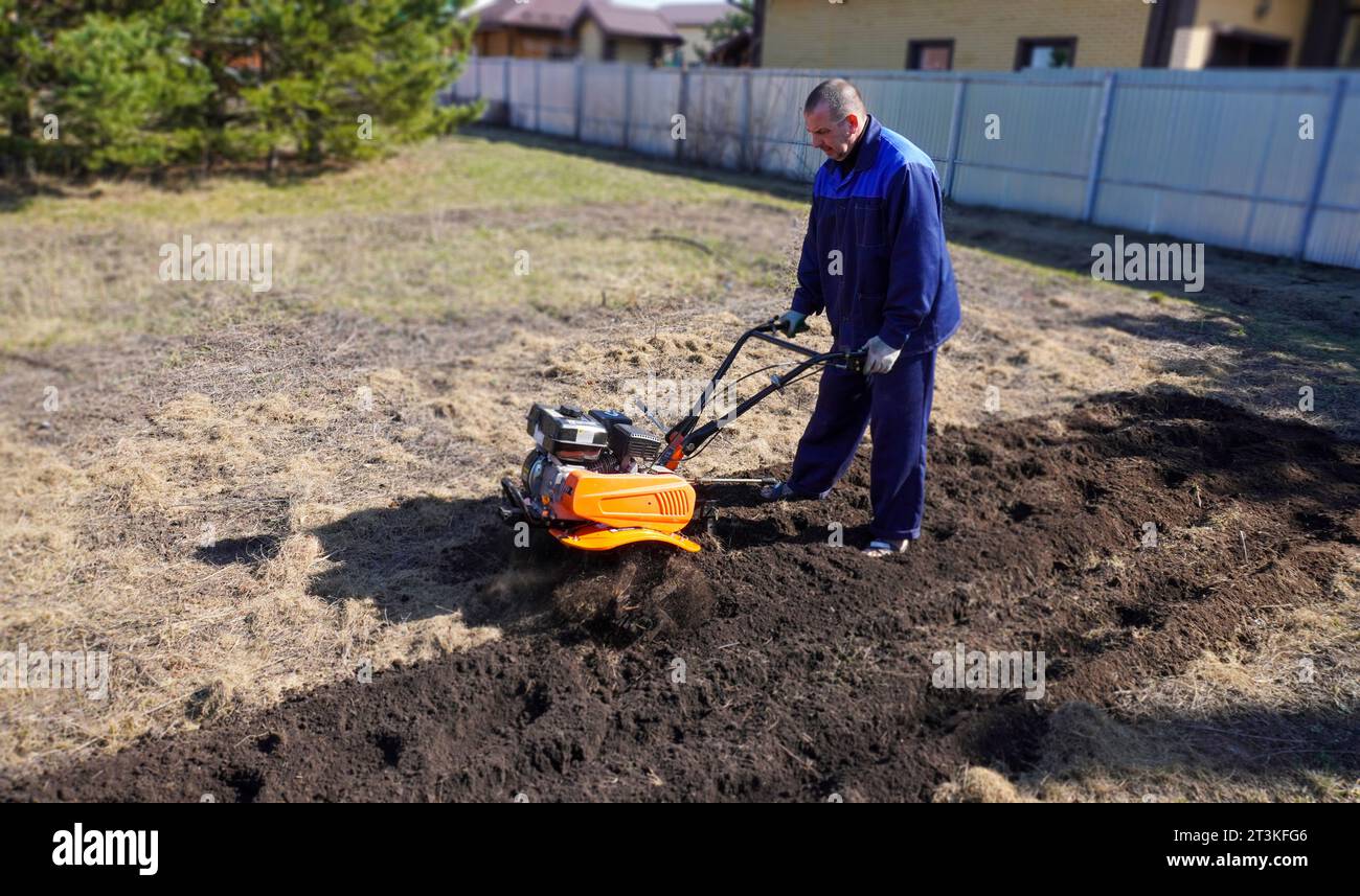 A man works in a vegetable garden in early spring. Digs the ground ...