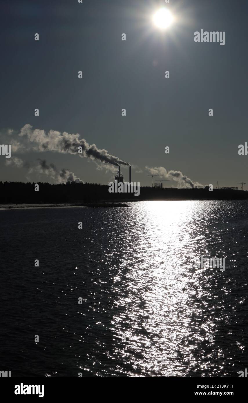 sunshine on the surface of the sea with industrial smokes in Oulu, Finland Stock Photo