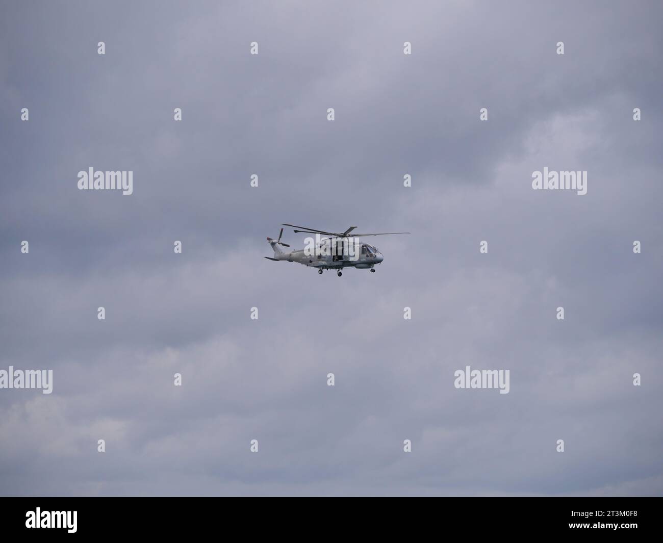 A Gray English Coast Guard Helicopter Hovers With Door Open Against A 