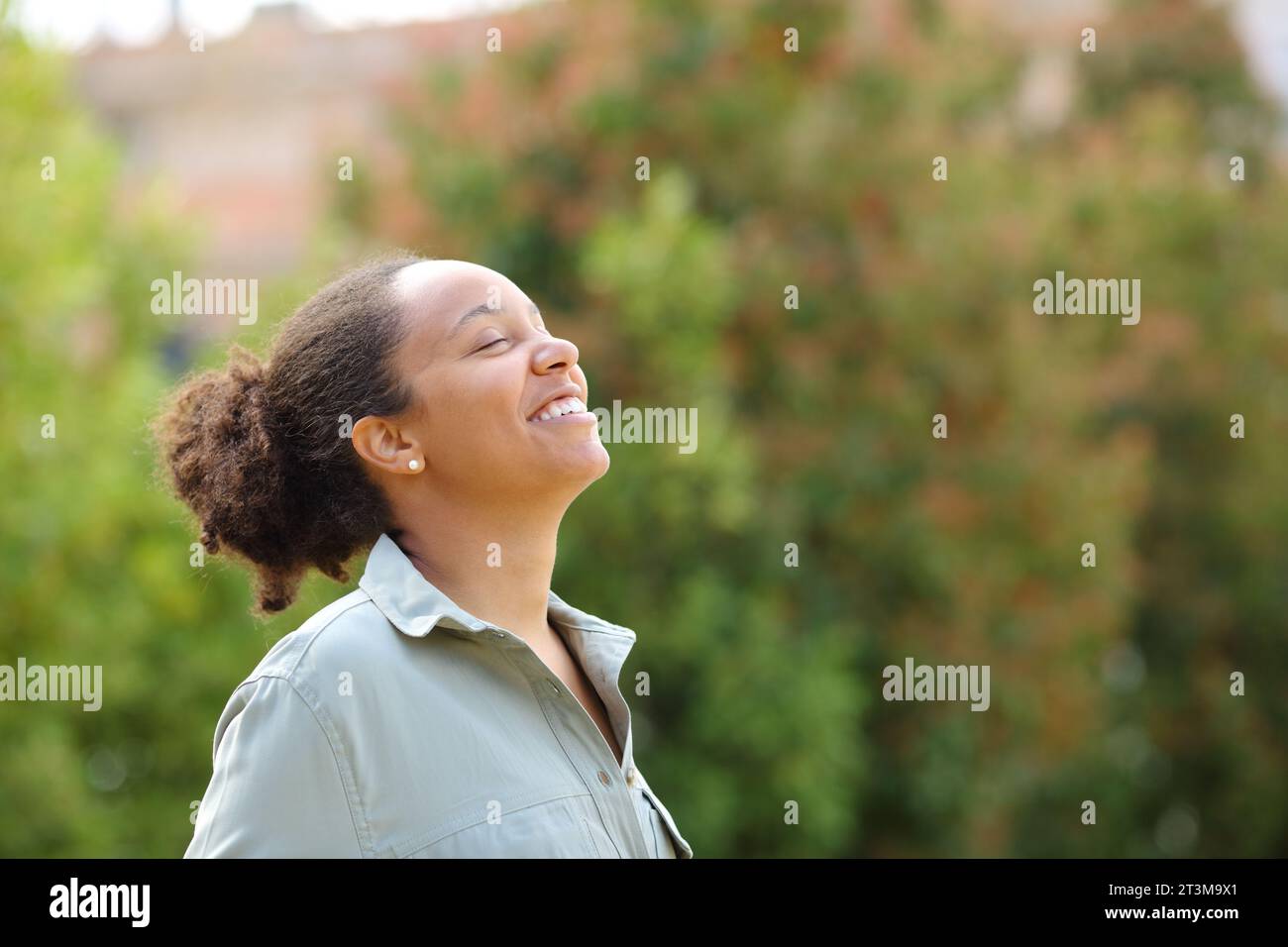 Happy black woman breathing fresh air in a green garden Stock Photo