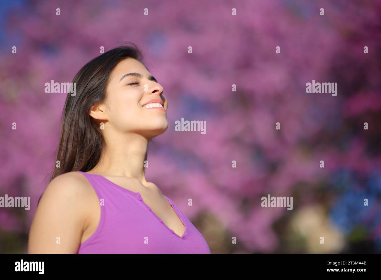 Happy woman breathing fresh air on violet background in a park Stock Photo