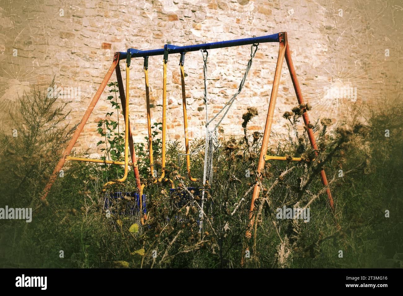 Abandoned swing in thistles in scary, grungy image. Stock Photo