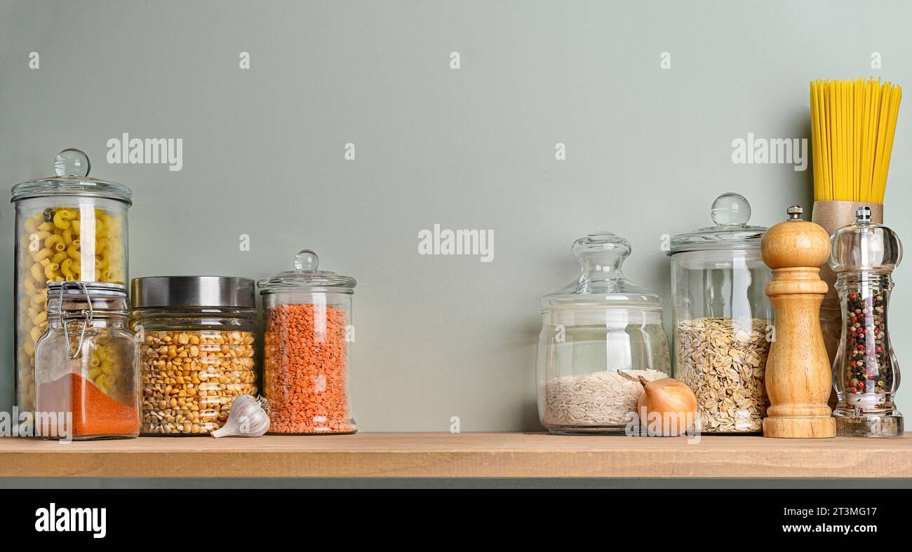 Kitchen shelf for storing food in glass jars on a pastel green wall