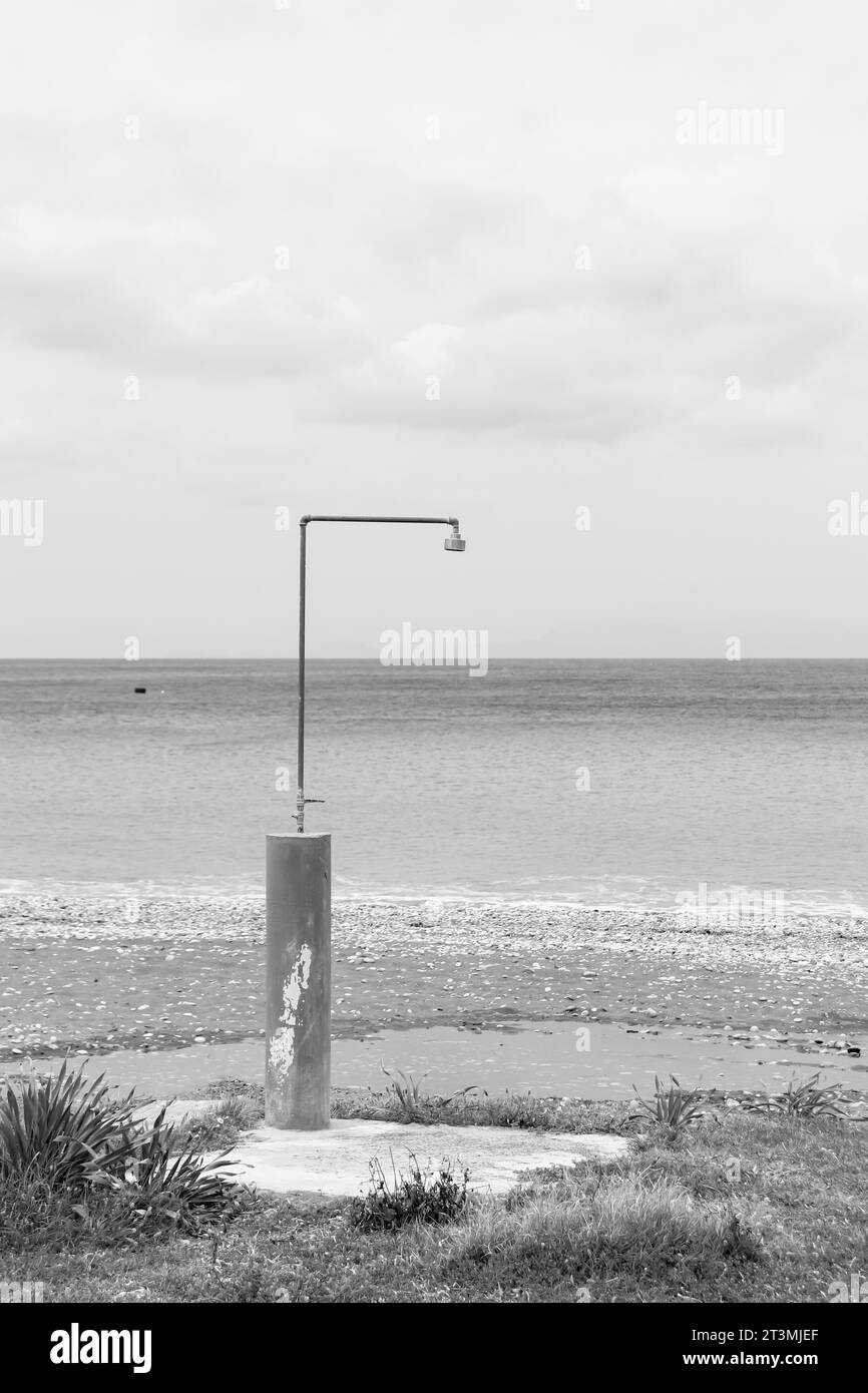 Outdoor beach shower in front of the ocean at Paralia Ixia beach in black and white Stock Photo