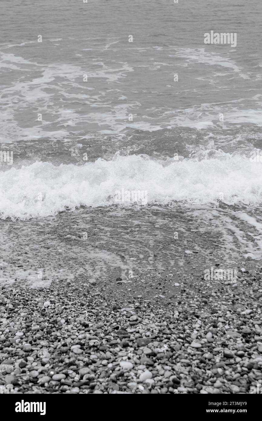 Clear water washing up on the shore at Paralia Ixia beach off Rhodes city in black and white Stock Photo