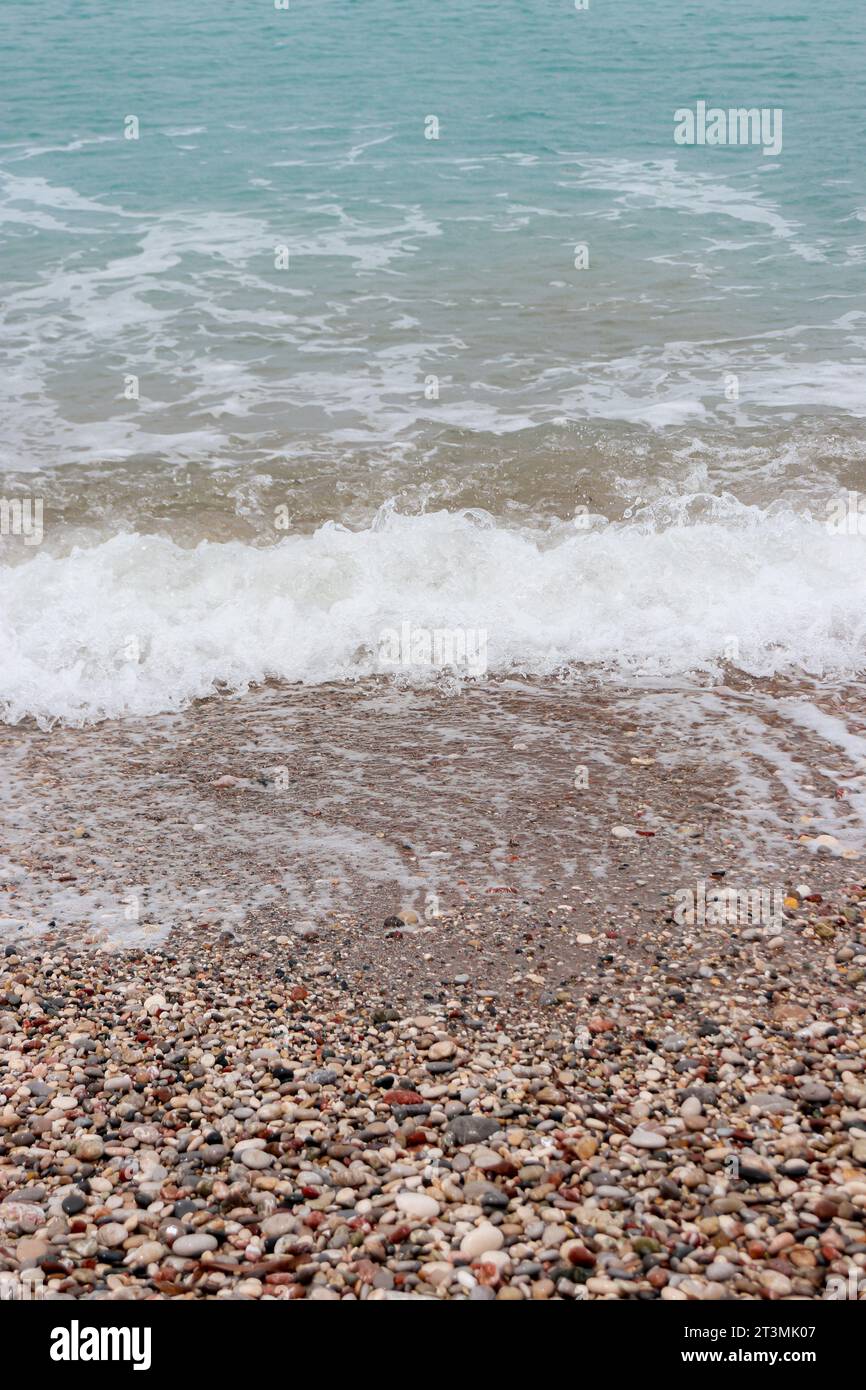 Clear water washing up on the shore at Paralia Ixia beach off Rhodes city creating a turquoise and brown gradient Stock Photo