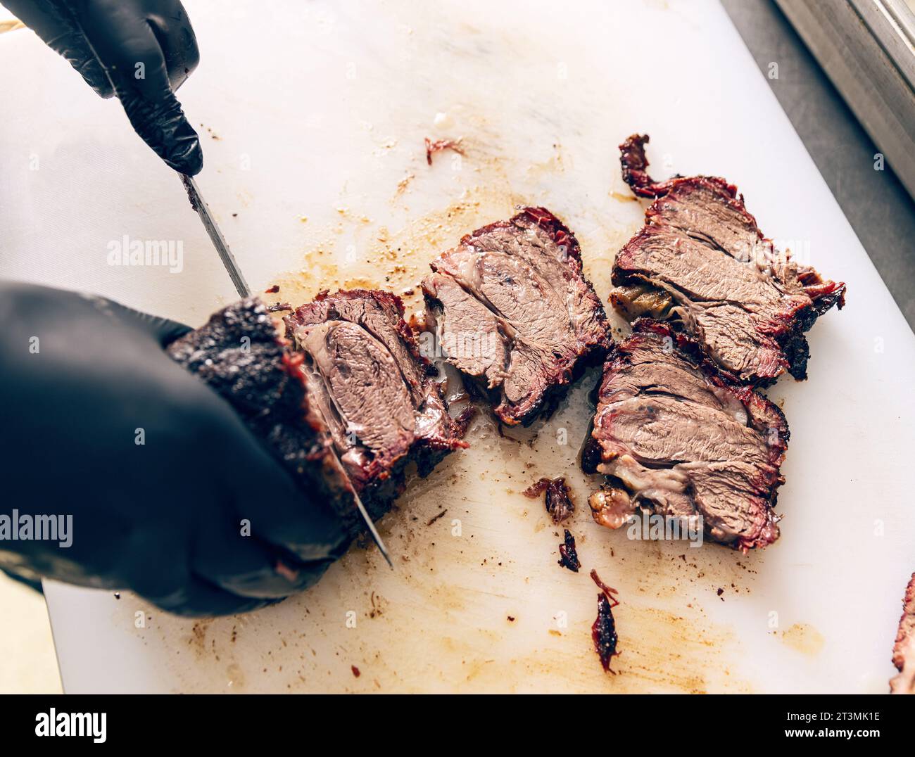 Chef hands cut grill steak at kitchen restaurant. Closeup chef hands cut meat. Professional cutting grill meat at chopping board. Stock Photo
