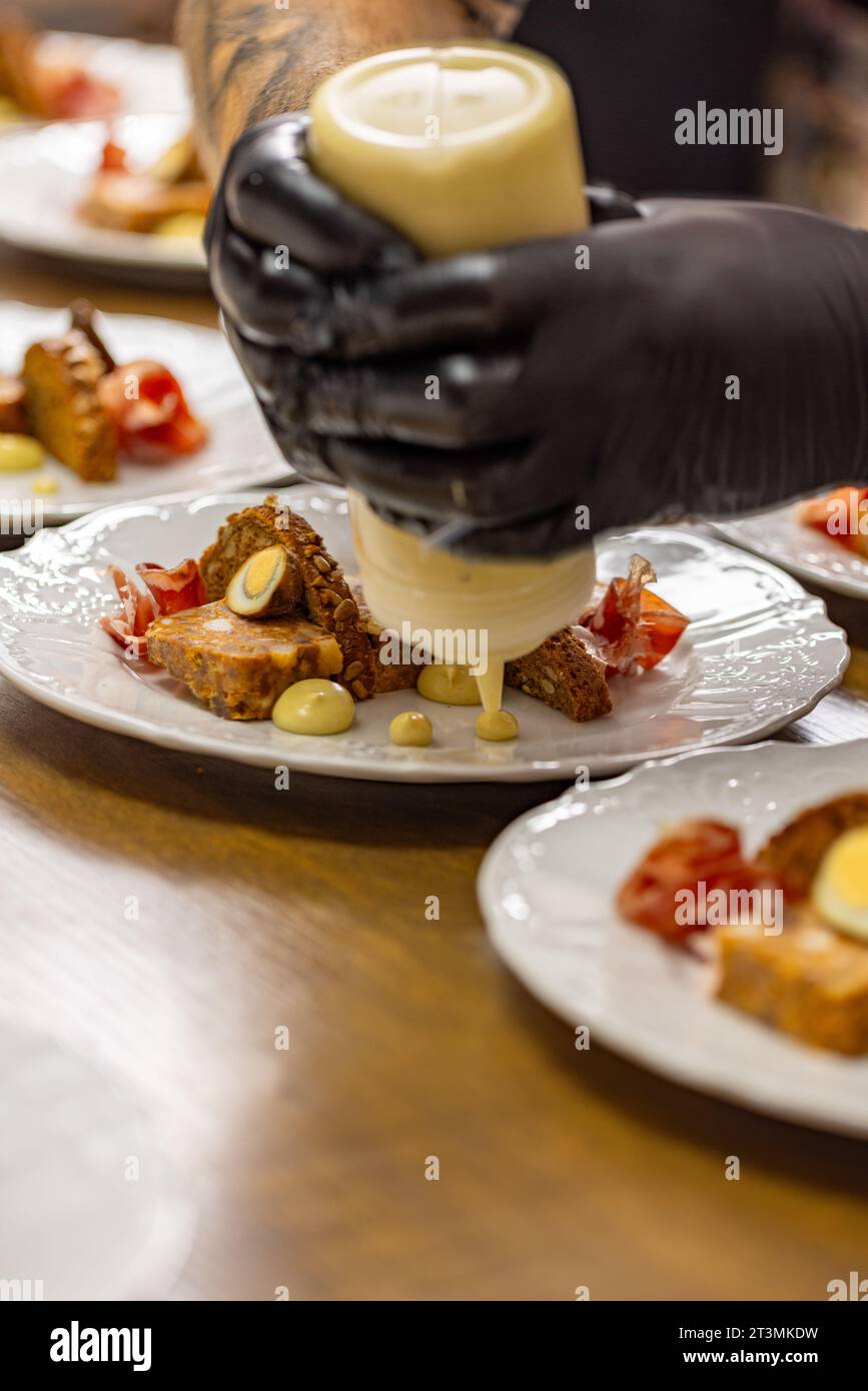 Chef's hand skillfully drizzling sauce over a beautifully plated dish Stock Photo