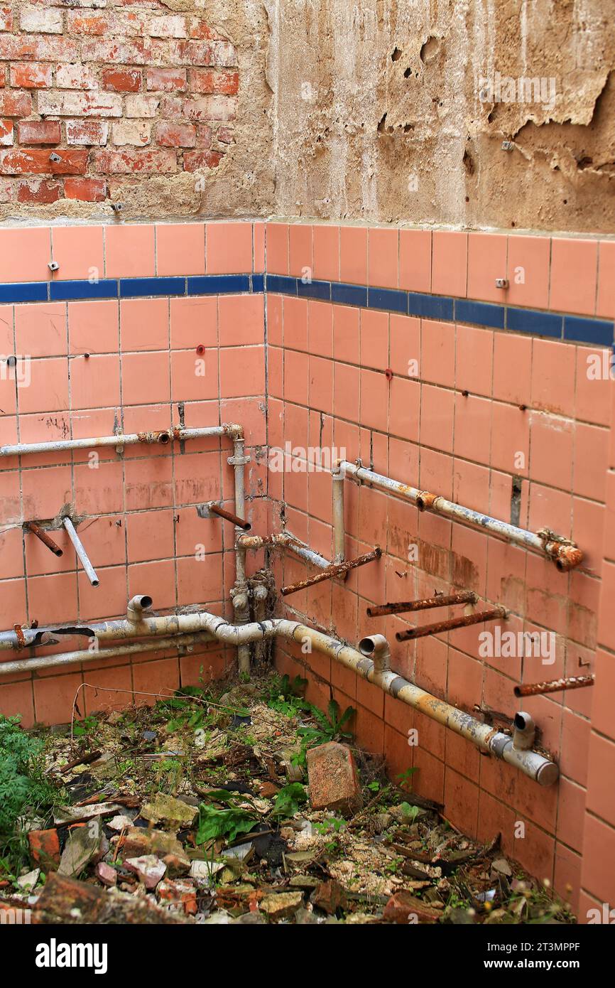 Rusty pipes in desolate remains of a bathroom. Stock Photo
