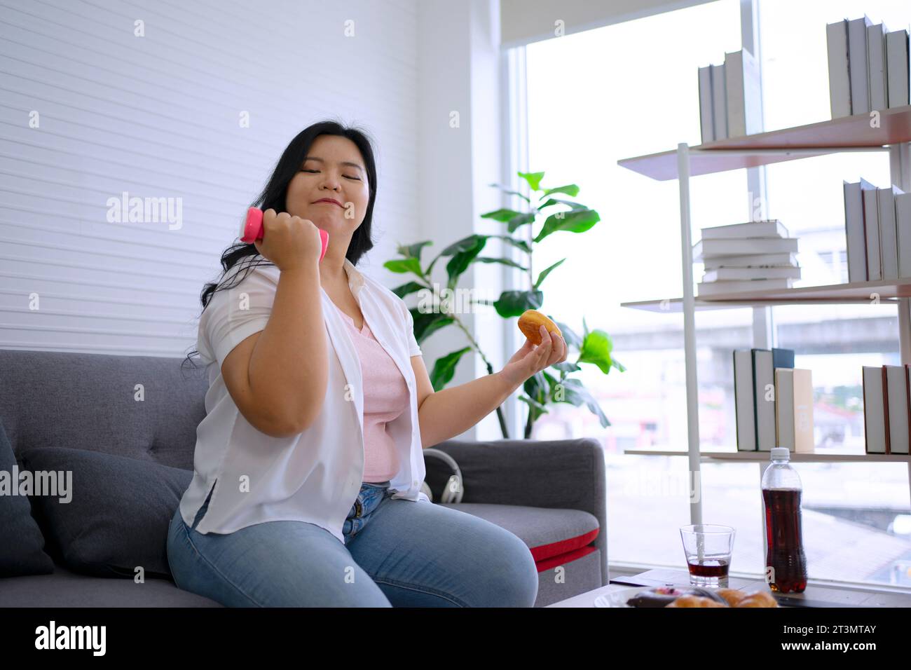 Plus size woman is eating donut. Health care and lifestyle concept. Stock Photo