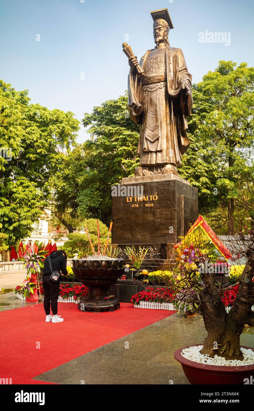 A young Vietnamese man prays and offers incense at the giant bronze statue of legendary emperor Ly Thai To in central Hanoi Stock Photo