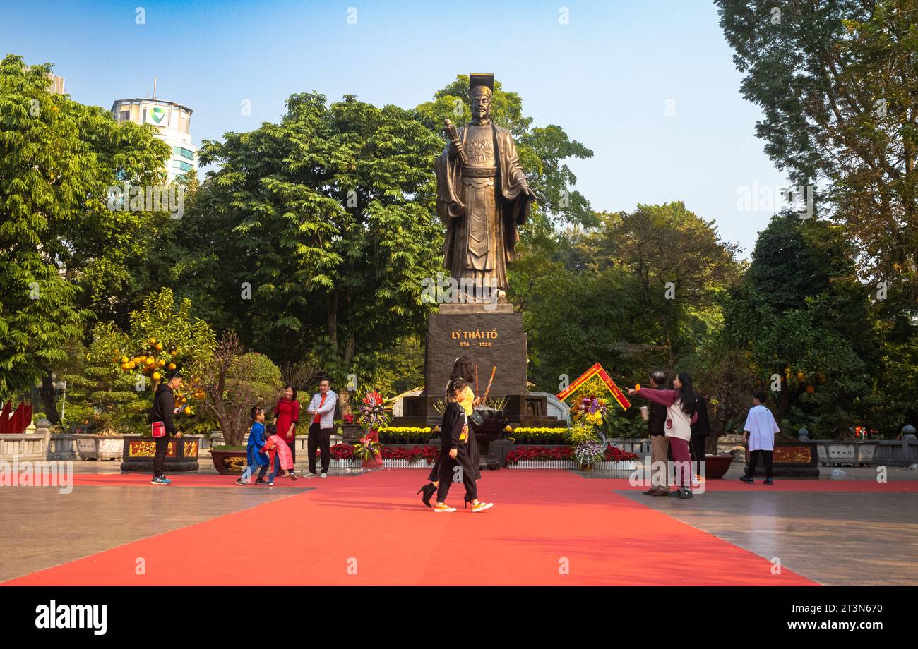 Vietnamese people walk next to the giant bronze statue of legendary emperor Ly Thai To in central Hanoi Stock Photo