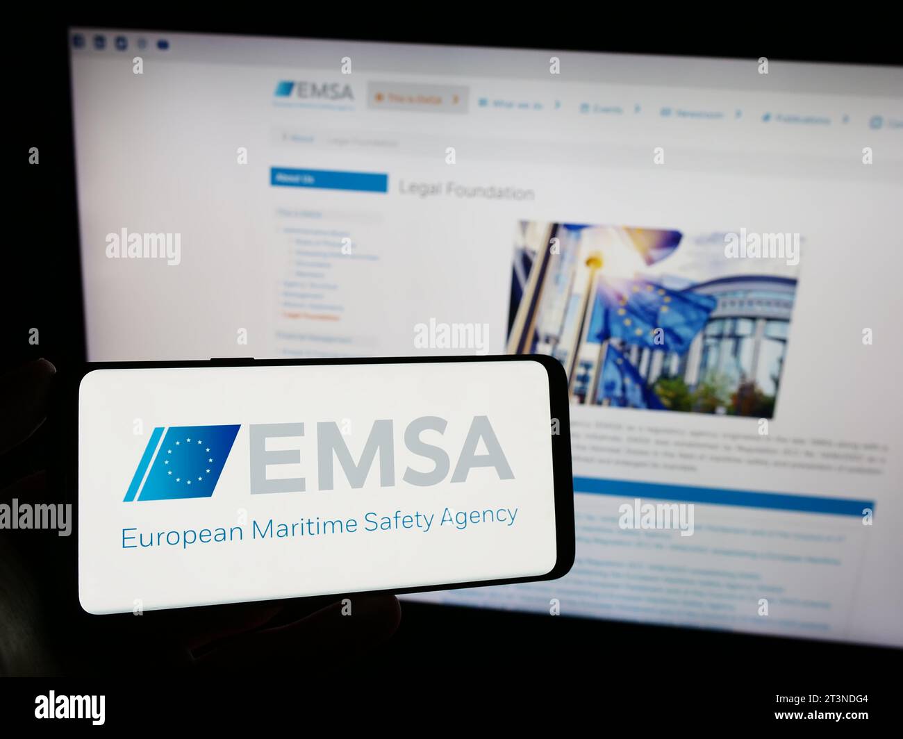 Person holding smartphone with logo of EU institution European Maritime Safety Agency (EMSA) in front of website. Focus on phone display. Stock Photo