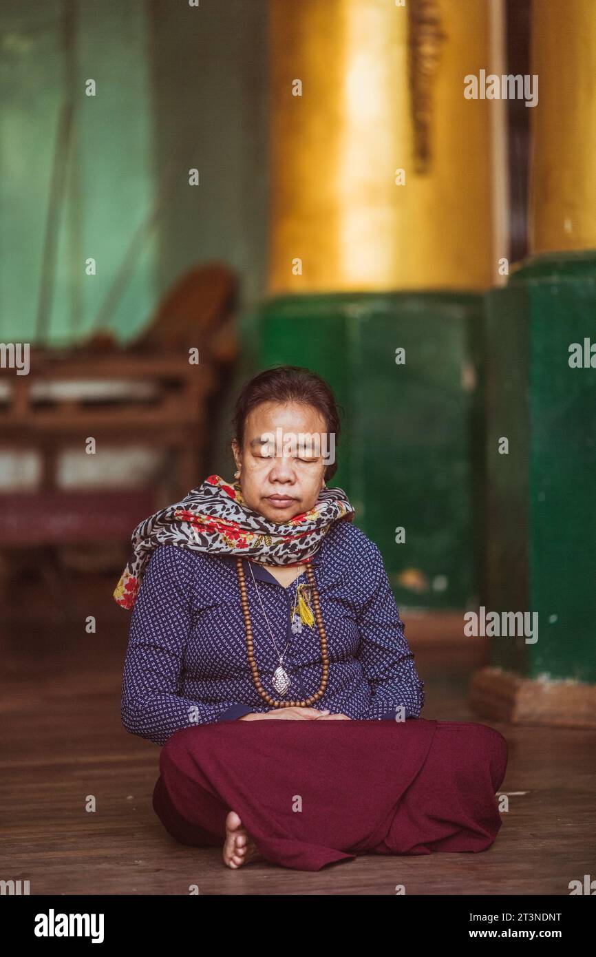Myanmar, February 18, 2023: Woman meditates at the Shwedagon Pagoda, Yangon, Myanmar. Stock Photo