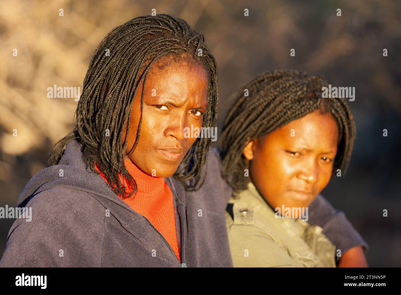 two young african woman with braids , portrait outdoors in the village ...