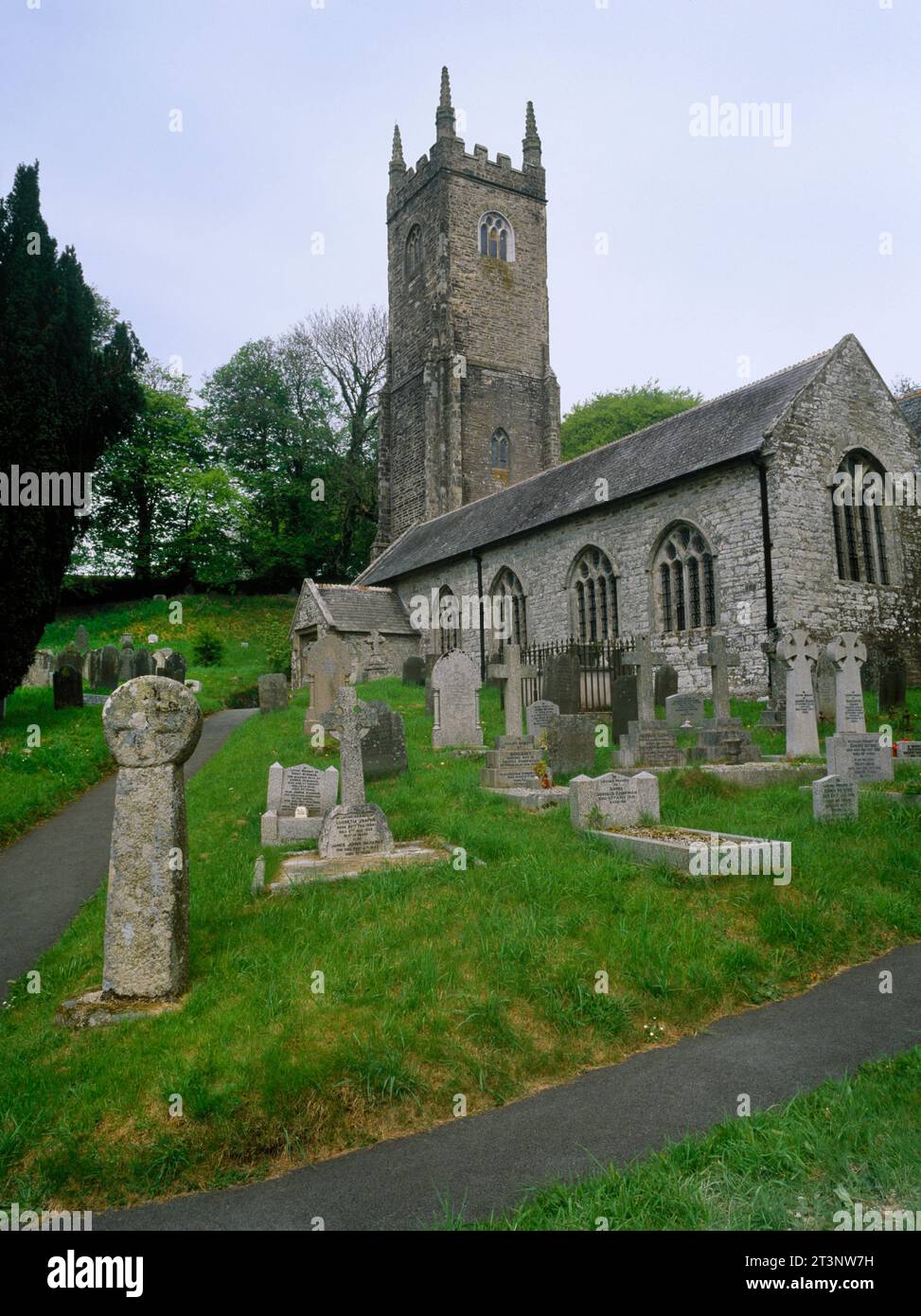 View NW of St Nonna's Church, Altarnun, Cornwall, England, UK, with an ancient cross-head re-erected on a modern shaft by the SE churchyard gate. Stock Photo