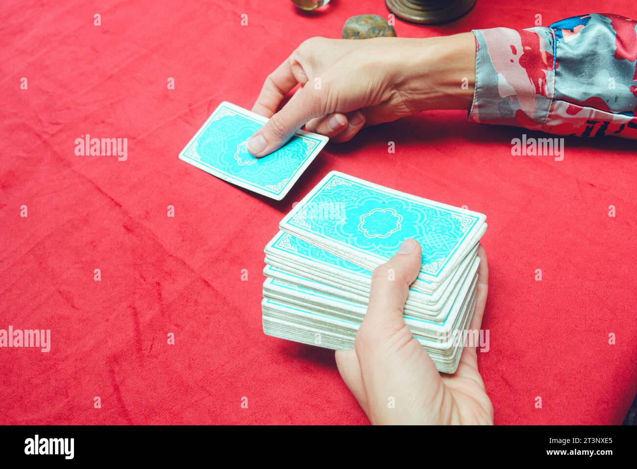 first person top view of unrecognizable caucasian woman placing blue tarot card on table with red tablecloth, tarot concept, copy space Stock Photo