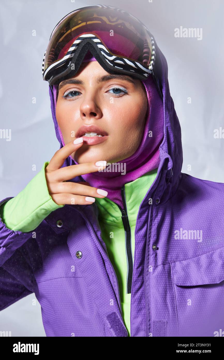 pretty woman in balaclava, purple winter jacket and ski googles posing