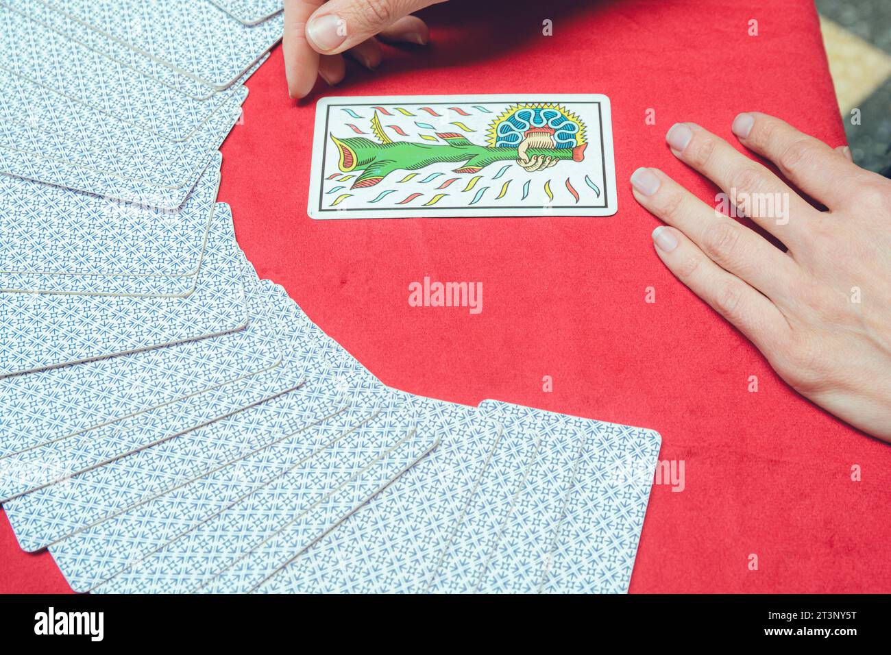 top view of unrecognizable caucasian tarot reader woman, sitting starting therapeutic reading, taking out and turning over card from deck and placing Stock Photo