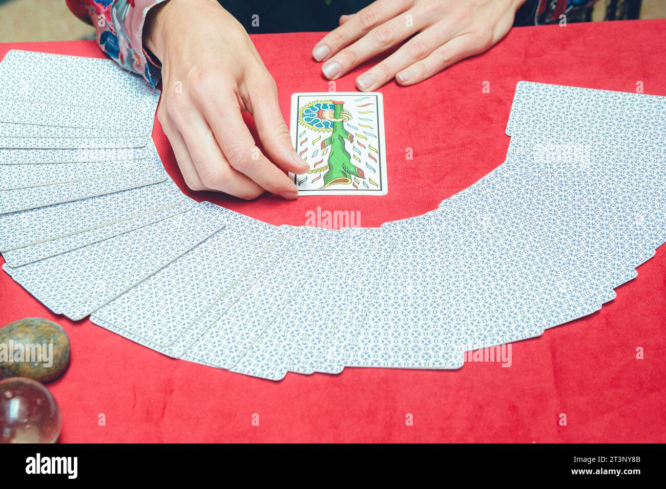 top view of unrecognizable caucasian tarot reader woman, sitting starting therapeutic reading, taking out and turning over card from deck and placing Stock Photo