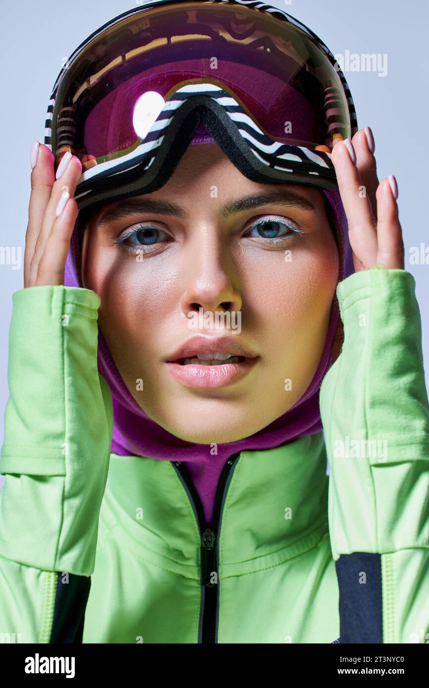 pretty woman in winter active wear with balaclava on head adjusting ski