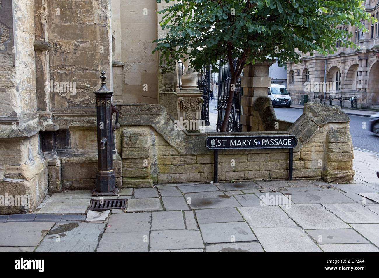 Old water pump in St Mary's Passage, Oxford city centre. To the left of the pump is a benchmark symbol in the church's stonework used by surveyors in Stock Photo