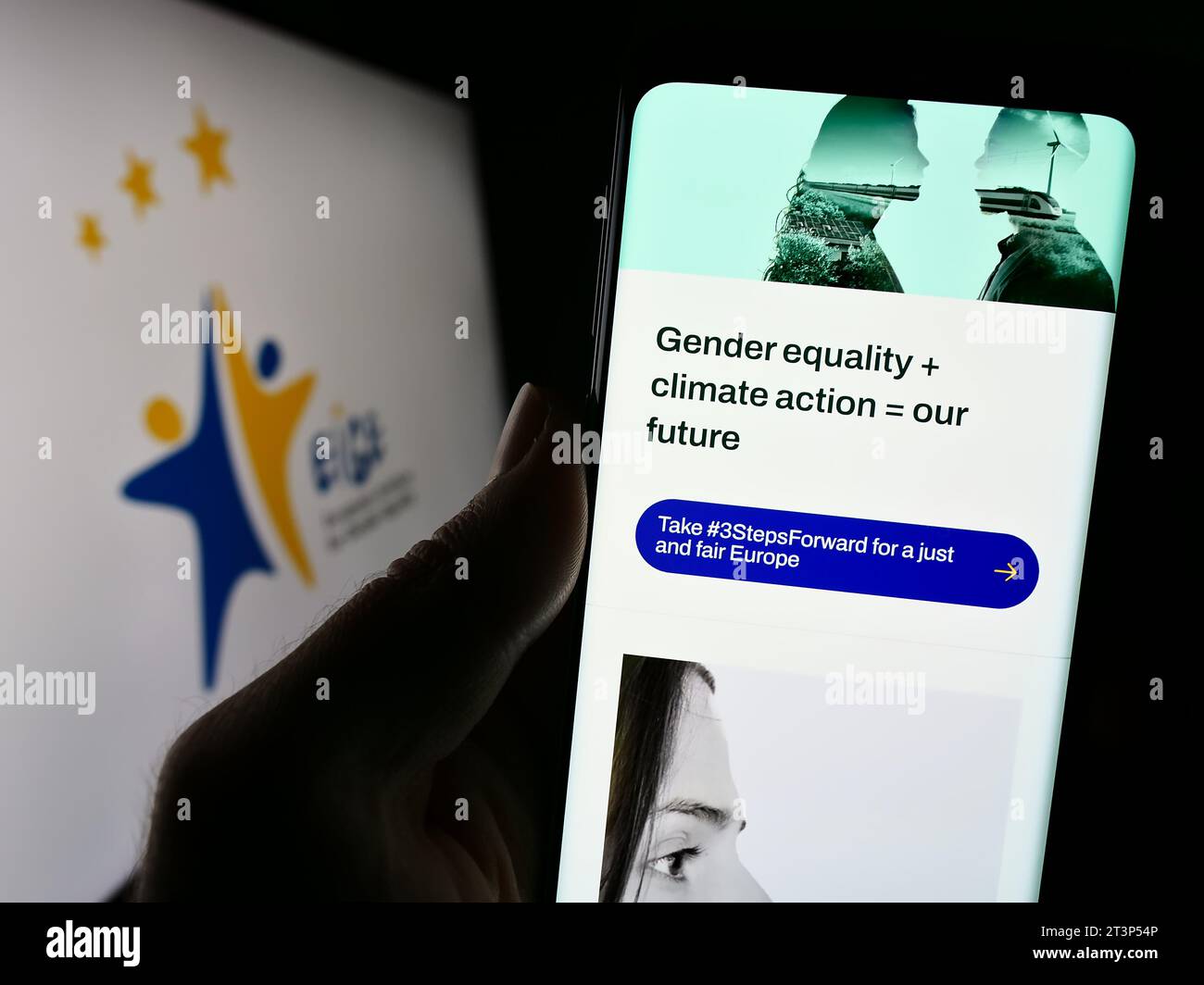 Person holding smartphone with webpage of European Institute for Gender Equality (EIGE) in front of logo. Focus on center of phone display. Stock Photo