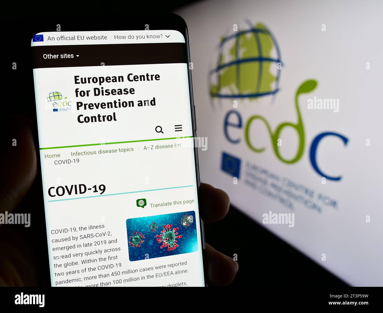 Person holding cellphone with webpage of European Centre for Disease Prevention and Control (ECDC) with logo. Focus on center of phone display. Stock Photo