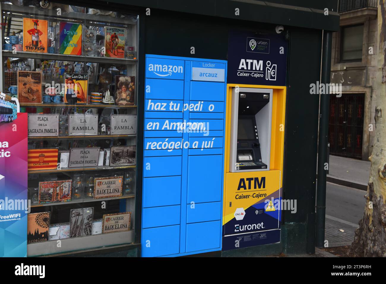 ATM machine alongside Amazon pick up point at a gift shop in Barcelona- In Barcelona Spain 31 July 2023 Stock Photo