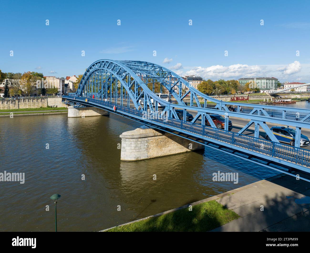 Krakow, Poland. Pilsudski blue tied arc bridge over Vistula River with cars, bus, tramway tracks, footbridge and walkway for pedestrians and bicycle l Stock Photo