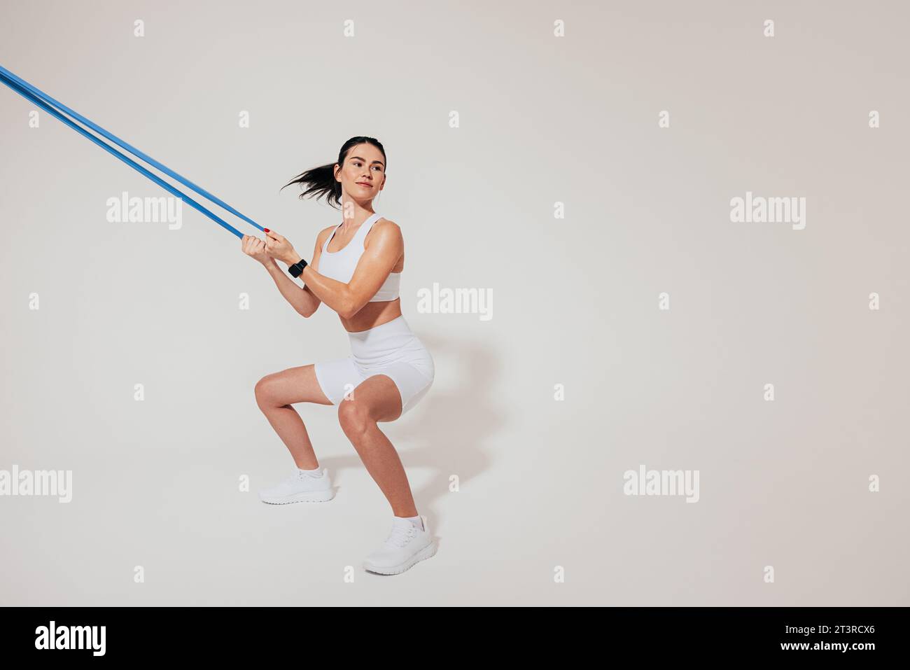 Young slim woman doing sit-ups and using a resistance band Stock Photo