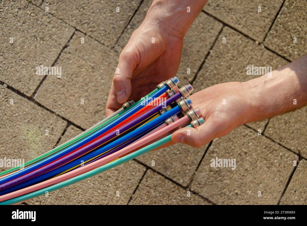 Fibre optic cable in the hands of a man against the background of paving slabs. Stock Photo