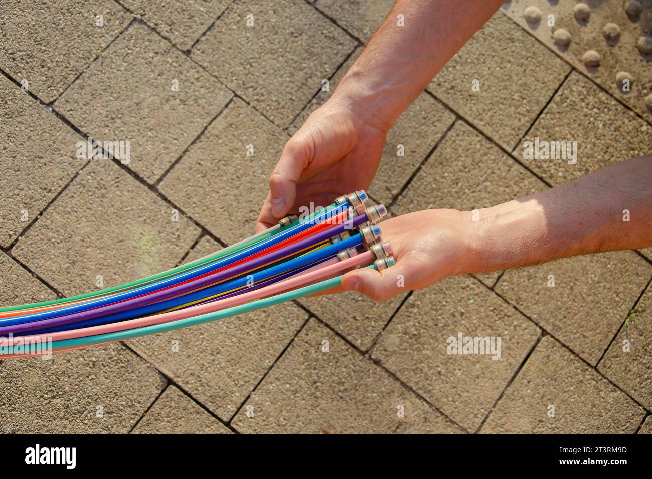 Fibre optic cable in the hands of a man against the background of paving slabs. Stock Photo
