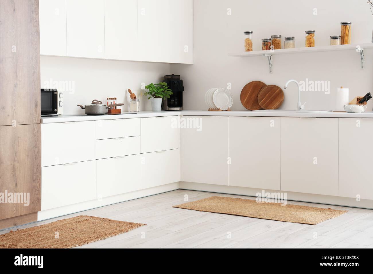 Interior of light kitchen with counters and wicker carpets Stock Photo ...