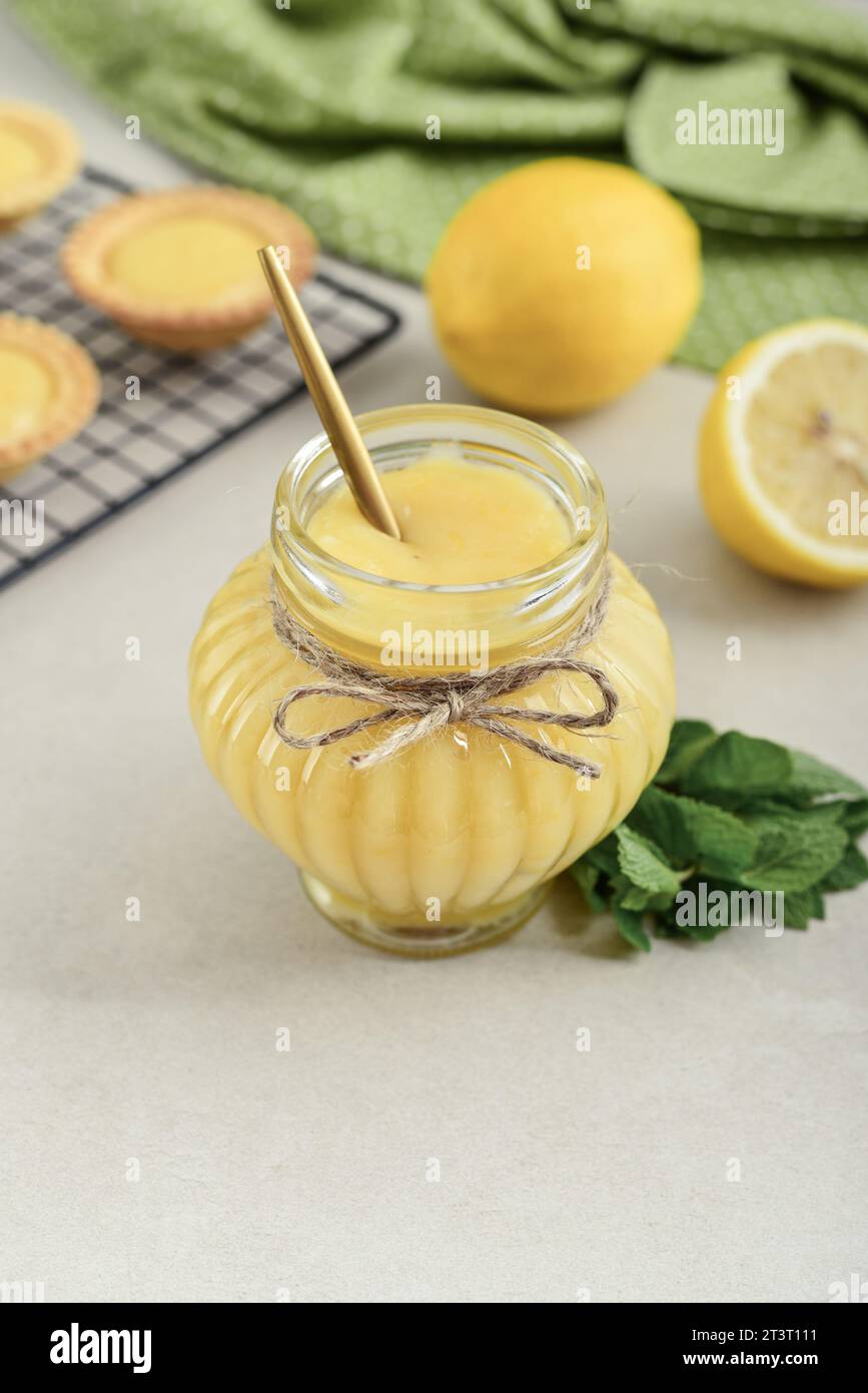 Homemade lemon curd in glass jar with fresh lemons on wooden cuttig board closeup Stock Photo
