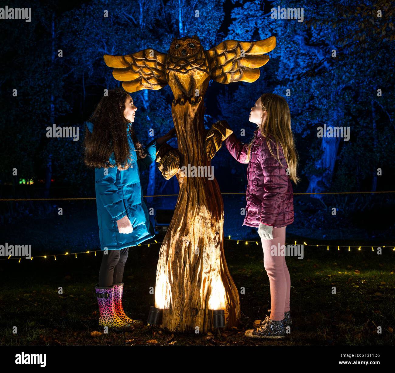Gosford Estate, East Lothian, Scotland, UK, 26th October 2023. Wondrous Woods Illuminations event: visitors enjoy the night event in the grounds of Gosford House. Pictured: Mia (aged 10 years) and Ellie (aged 9 years) are enchanted by a sculpture along the trail. Credit: Sally Anderson/Alamy Live News Stock Photo