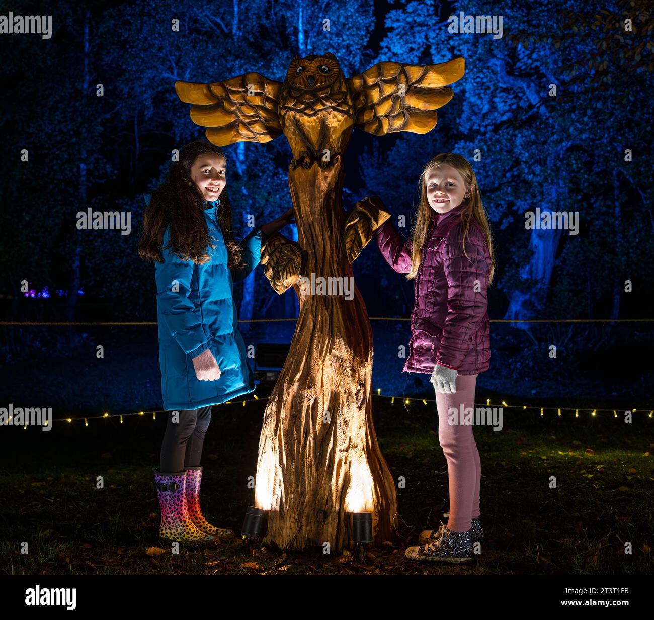 Gosford Estate, East Lothian, Scotland, UK, 26th October 2023. Wondrous Woods Illuminations event: visitors enjoy the night event in the grounds of Gosford House. Pictured: Mia (aged 10 years) and Ellie (aged 9 years) are enchanted by a sculpture along the trail. Credit: Sally Anderson/Alamy Live News Stock Photo