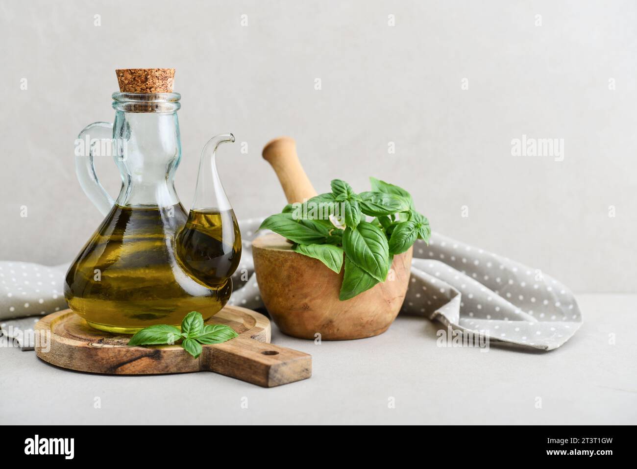 Olive oil in vintage bottle with basil and wooden cutting board  on light background Stock Photo