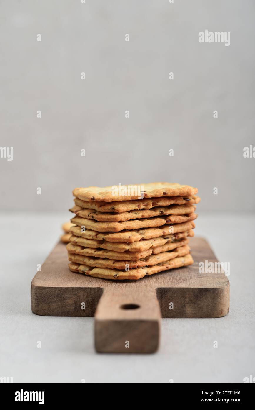 Multigrain crunchy cookies with flax and sesame seeds on wooden cutting board on light background Stock Photo