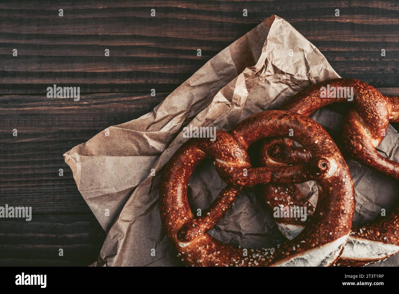 Two soft pretzels with sesame seeds on wooden background, top view Stock Photo