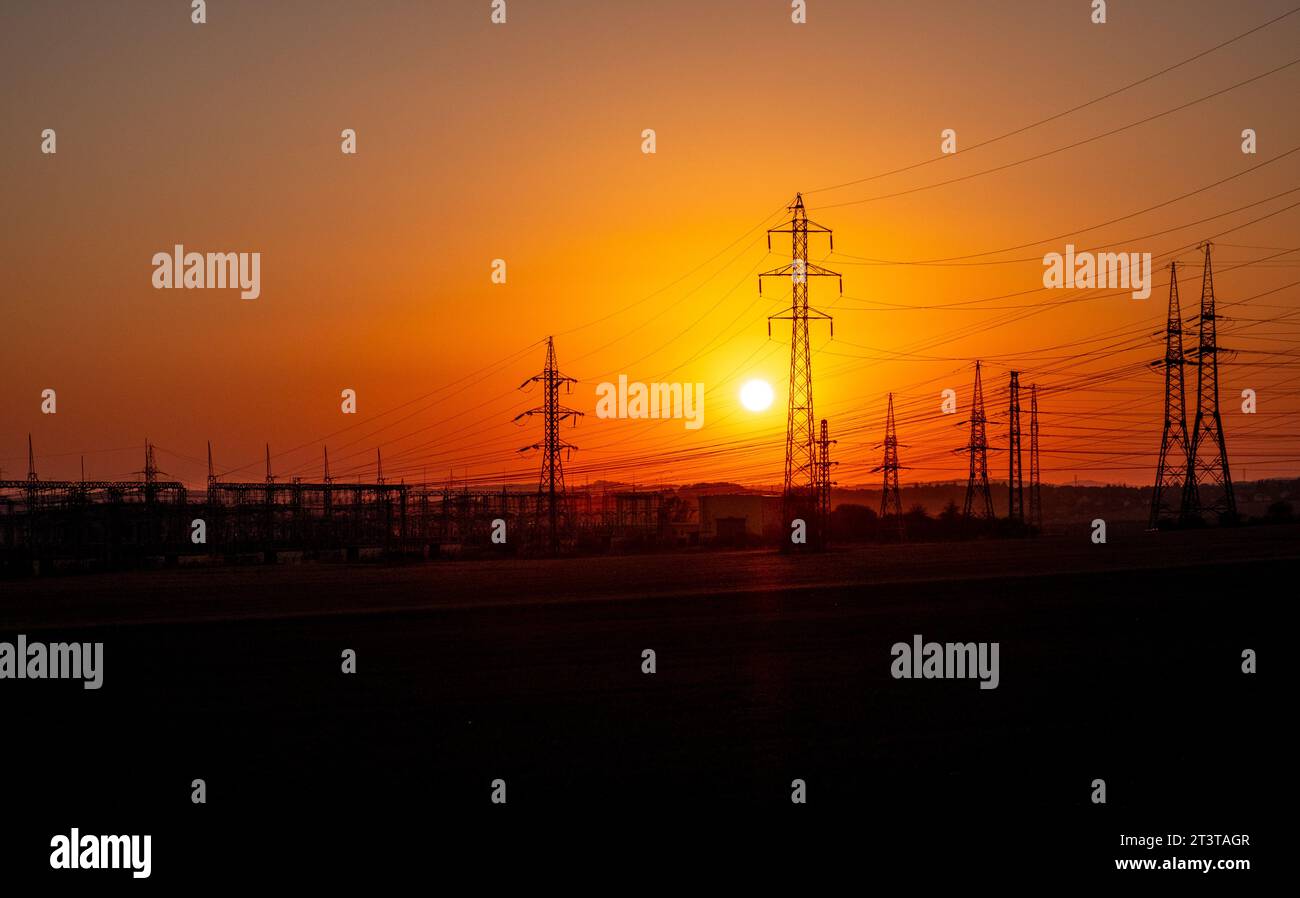 sunset behind power station, high-tension wires in sunset Stock Photo