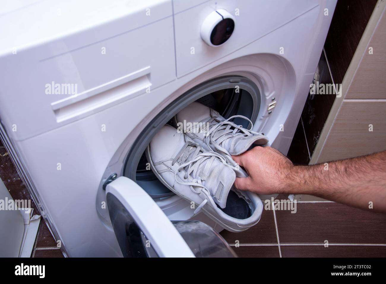 Top view of putting dirty old sneakers into washing machine Stock Photo