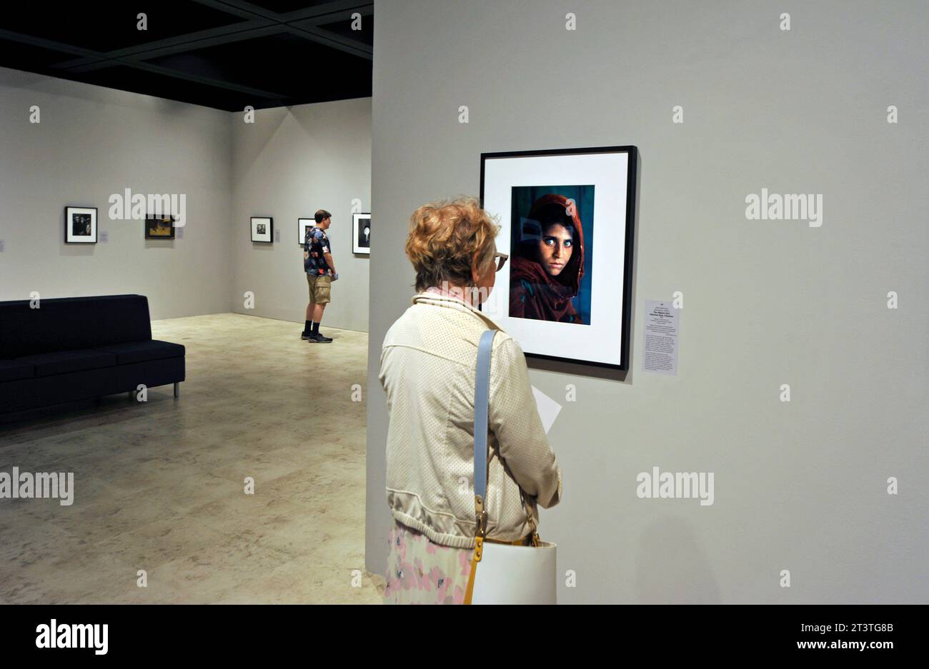 A woman studies the Afghan Girl photograph by Steve McCurry in the Power of Photography exhibit at the Bowers Museum, Santa Ana, California, USA Stock Photo