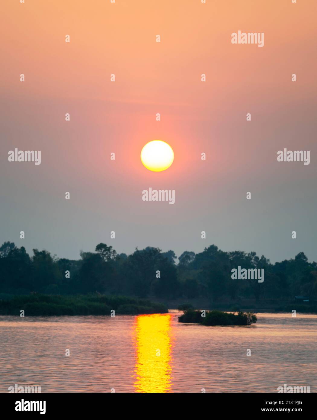 Silhouette of human figure in small,narrow motot boat,drifting across the calm,peaceful waters of the Mekong,through rays of golden light reflected on Stock Photo