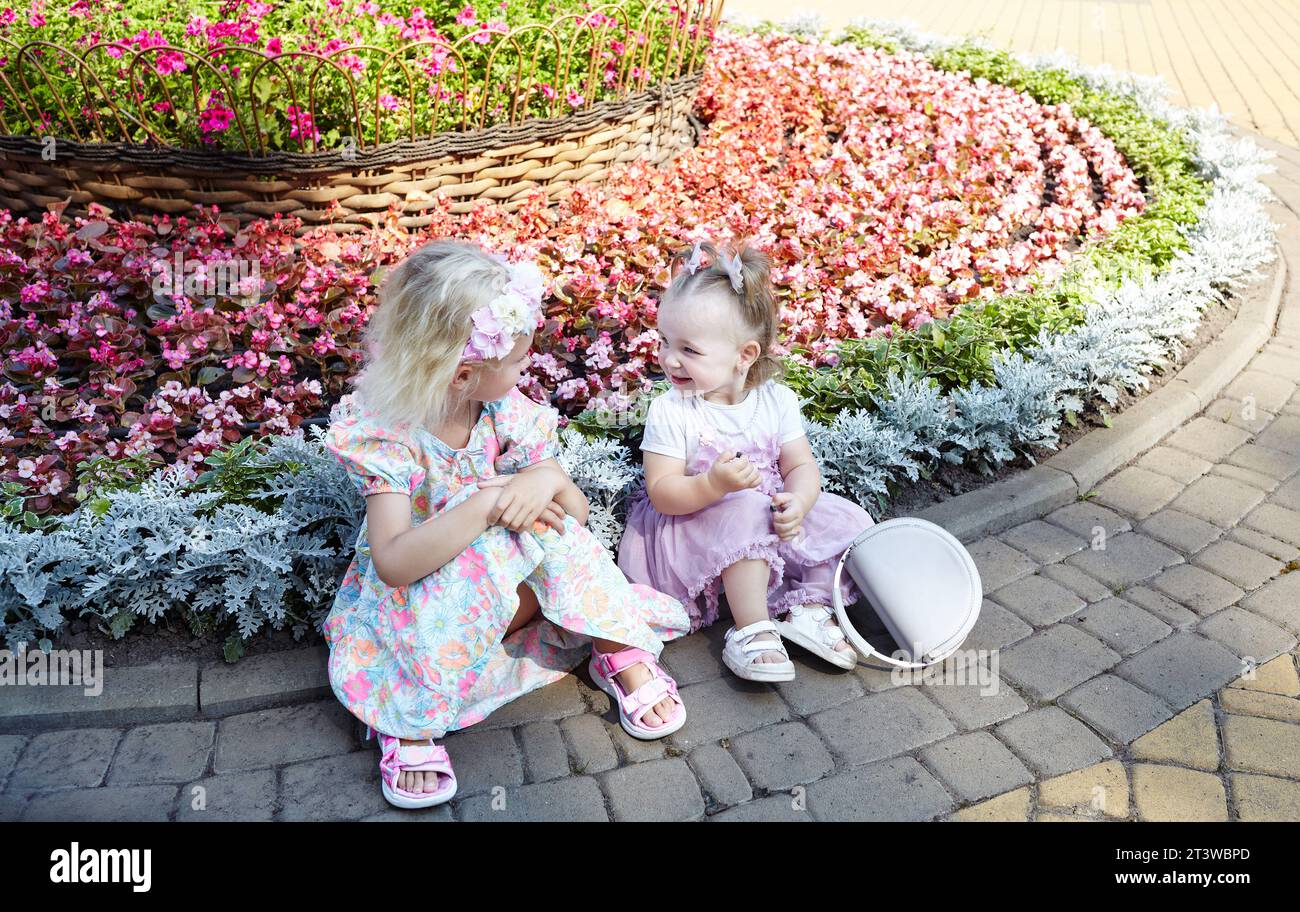 Stylish little girls relax in summer city park. Adorable little children have a good time. Childhood Stock Photo