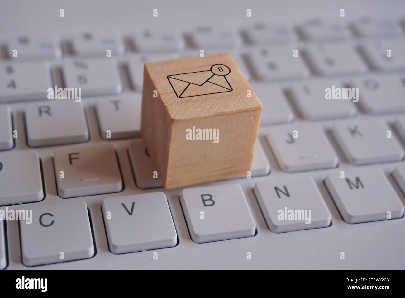 Wooden cube with new email notification icon on top of keyboard. Communication and technology concept Stock Photo