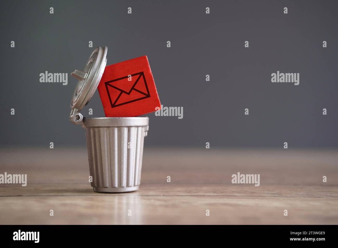 Closeup image of wooden cube with mail icon inside trash can. Junk mail and spam mail concept. Stock Photo