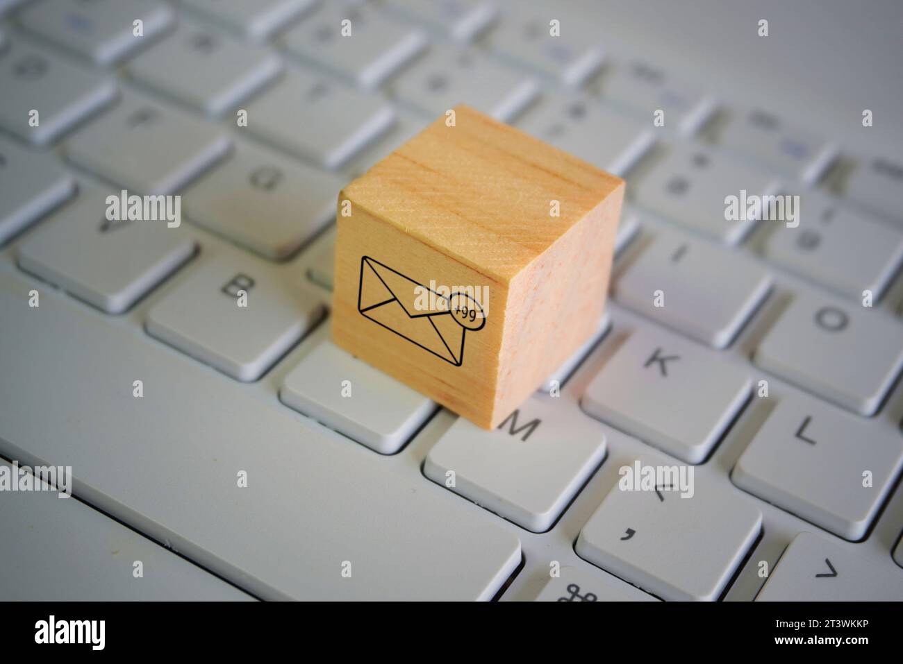 Wooden cube with new email notification icon on top of keyboard. Communication and technology concept Stock Photo